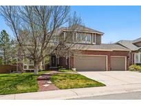Charming two-story home featuring a brick facade and a three-car garage, complemented by a well-manicured lawn at 10305 Charissglen Cir, Highlands Ranch, CO 80126