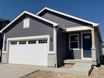 Charming gray house boasts a white garage door, stone accents, and a covered entryway with a dark blue door at 9085 Rifle St, Commerce City, CO 80022