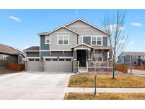 Charming two-story home with a three-car garage, covered porch, and gray and blue siding at 11010 Worchester St, Commerce City, CO 80022