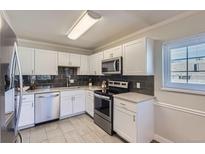 Bright kitchen featuring white cabinets, stainless steel appliances, gray backsplash and tile flooring at 6800 E Tennessee Ave # 382, Denver, CO 80224