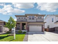 Charming two-story home featuring a manicured lawn, inviting front porch, and a two-car garage at 1846 Osprey Dr, Brighton, CO 80601