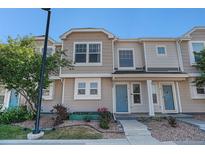 Charming multi-level townhouse showcasing neutral siding, beautiful landscaping, and an inviting blue front door at 18954 E 57Th Pl # D, Denver, CO 80249