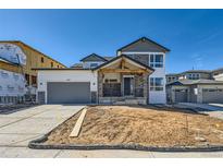 New two-story home featuring a two-car garage and a covered porch with stone accents at 6391 Cristobal Pt, Parker, CO 80134