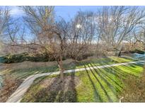 Sunny backyard with mature trees and a paved pathway at 655 S Alton Way # 4B, Denver, CO 80247