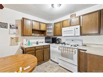 Eat-in kitchen with wood cabinets and white appliances at 655 S Alton Way # 4B, Denver, CO 80247