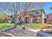 Inviting townhome with a charming brick facade, well-maintained landscaping, and an American flag on display at 6406 Silver Mesa Dr # F, Highlands Ranch, CO 80130