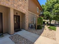 Inviting home entrance with a charming brown door, stone accents, and well-maintained landscaping at 1122 Olympia Ave # 12H, Longmont, CO 80504