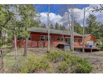 Charming wood home featuring a hot tub and deck surrounded by lush greenery and aspen trees at 26367 Pressler St, Conifer, CO 80433