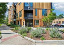 Modern condo building featuring wood paneling, black accents, and landscaped front yard at 1601 Park Ave # 106, Denver, CO 80218