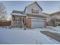 Two-story house with gray siding, red brick accents, and a snow-covered front yard at 2576 S Ensenada Way, Aurora, CO 80013