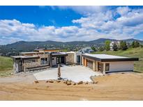 Stunning contemporary home with stone accents and a large concrete driveway, set against a scenic mountain backdrop at 545 Strada Rossa Rd, Golden, CO 80401