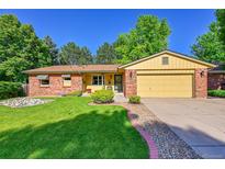 Charming brick and yellow home with a well-manicured lawn and mature trees at 12348 Elizabeth Ct, Thornton, CO 80241