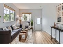 Bright living room featuring neutral walls, light wood floors, large windows, and comfortable furnishings at 6065 Wadsworth Blvd # A, Arvada, CO 80003
