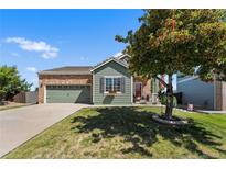 Charming single-Gathering home featuring a brick and green exterior, a well-manicured lawn and a two-car garage at 19771 E Wesley Pl, Aurora, CO 80013