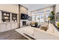 Bright living room with fireplace, built-ins, and large windows offering community views at 7214 S Shady Grove Ct, Aurora, CO 80016