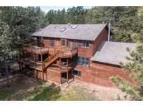 Stunning exterior view of a multi-story home with a spacious wooden deck surrounded by lush trees at 133 Mine Ln, Boulder, CO 80302