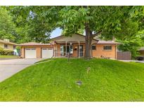 Charming brick home with a well-manicured lawn and mature tree providing shade and curb appeal at 2876 S Wolff St, Denver, CO 80236