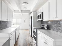 Bright kitchen featuring stainless steel appliances, gray subway tile backsplash, and white cabinets at 7877 E Mississippi Ave # 901, Denver, CO 80247