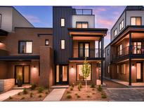 Stunning modern townhome with brick and metal exterior, balcony, and landscaped front yard at dusk at 9066 Harlan St, Westminster, CO 80031