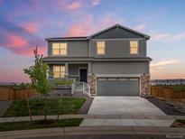 Two-story home featuring stone accents and a two-car garage under a beautiful dusk sky at 8807 Sedalia St, Commerce City, CO 80022