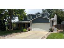Two-story home featuring gray siding, stone accents, mature trees, and a driveway leading to an attached two-car garage at 5914 S Kearney St, Centennial, CO 80111