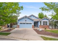 Charming blue home featuring a two-car garage, brick accents, and a well-maintained front yard at 1118 S Duquesne Cir, Aurora, CO 80018