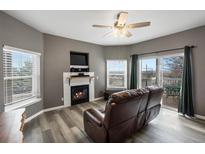 Cozy living room with a fireplace, TV, ceiling fan, and access to a private balcony with views at 2428 W 82Nd Pl # 2D, Westminster, CO 80031