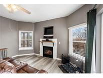 Cozy living room features a fireplace with mantel and plenty of natural light from the windows at 2428 W 82Nd Pl # 2D, Westminster, CO 80031
