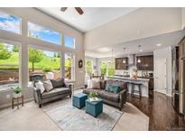 Bright living room featuring large windows with backyard views and an open floor plan to the kitchen at 13942 W 87Th Dr, Arvada, CO 80005