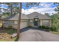 Charming single-story home with stone accents, a two-car garage, a well-manicured lawn, and mature trees at 31042 Wildwoods, Evergreen, CO 80439