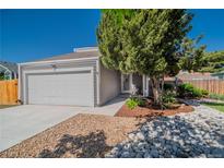Charming home featuring a two-car garage and landscaped front yard with river rock and mature trees at 87 Macon Ct, Aurora, CO 80010