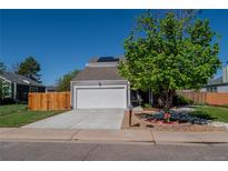 Home exterior showcasing a two-car garage, landscaped front yard, mature tree, and well-maintained lawn at 87 Macon Ct, Aurora, CO 80010