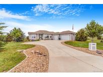 Sprawling ranch home featuring a long driveway, three-car garage, and pristine landscaping at 3221 Autumn Sun Cir, Castle Rock, CO 80104