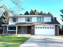 Charming two-story home with a well-maintained lawn, a two-car garage, and mature trees in the background at 4640 W Princeton Ave, Denver, CO 80236