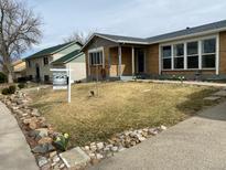 Charming brick home with a well-maintained lawn and a 'For Sale' sign, situated in a quiet neighborhood at 5456 Eagle St, Denver, CO 80239