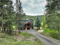 Beautiful two-story home with a covered front porch nestled among lush trees and picturesque surroundings at 31258 Niakwa Rd, Evergreen, CO 80439