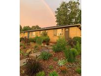 Charming home with a lush, landscaped front yard and a rainbow in the sky at 4332 Bruce Randolph Ave, Denver, CO 80207