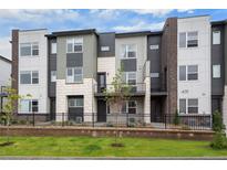 Modern townhome exterior featuring varied textures, landscaping, and a well-maintained front yard with a black metal fence at 479 Interlocken Blvd # 105, Broomfield, CO 80021