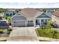 Gray two-story home featuring a three car garage and covered porch at 23913 E Swallow Cir, Aurora, CO 80016