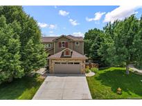 Charming two-story home featuring a stone-accented garage and a well-manicured front lawn with mature trees at 8532 W Eden Dr, Littleton, CO 80127
