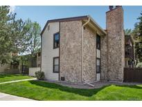 Well-maintained townhome featuring stone accents, neutral siding, and a manicured lawn at 7780 W 87Th Dr # E, Arvada, CO 80005