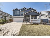 Charming two-story home with a covered front porch, manicured lawn, and a two-car garage at 10037 Idalia St, Commerce City, CO 80022