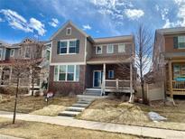Charming two-story home with gray siding, brick accents, and a welcoming front porch in a Gathering-friendly neighborhood at 21646 E Stroll Ave, Parker, CO 80138