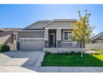 Charming home featuring a well-manicured lawn, covered porch, and attached two car garage at 10546 Boston St, Commerce City, CO 80640
