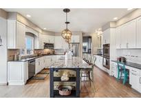 Spacious kitchen with white cabinets, stainless appliances, granite counters and large island at 8131 S Coolidge Way, Aurora, CO 80016