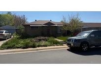 Modest single-story home with a small, overgrown front yard and a red front door at 7488 Quivas St, Denver, CO 80221