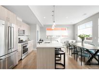 Bright, modern kitchen with stainless steel appliances, island with seating, and open floor plan at 1912 W 38Th Ave, Denver, CO 80211