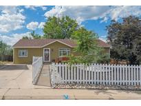 Charming single-story home featuring a welcoming entrance, white picket fence, and well-maintained landscaping at 1817 S Perry Way, Denver, CO 80219