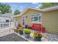 Charming home featuring a decorative red bench, colorful flower pots, and quaint exterior details at 1817 S Perry Way, Denver, CO 80219