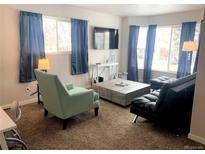 Cozy living room with neutral carpet, blue curtains, a flatscreen TV and a modern coffee table at 2200 W Moffat Pl, Denver, CO 80221